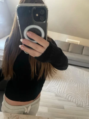 Svart stickad tröja med långa ärmar - En enkel och stilren svart stickad tröja med långa ärmar och ribbade muddar. Tröjan har en kroppsnära passform och är perfekt att matcha med både jeans och mjukisbyxor. Materialet ser mjukt och bekvämt ut.