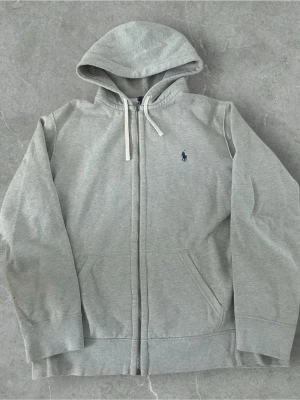 Ralph Lauren Zip Hoodie Grå XL -  📍Storlek:XL  💪🏽Skick:Ny utan prislapp   📐Mått:Längd:69cm:Bred:47:cm:  📎Material:86%Bomull:14%Polyester  📦Skickar alltid inom 24h  💸Köp fler plagg för att få billigare pris  ✅Äkthetsgaranti