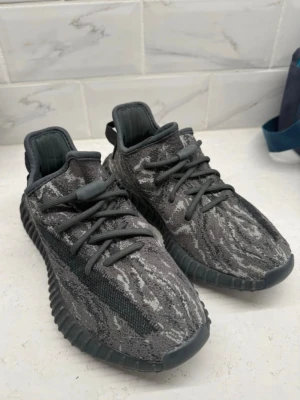 Adidas Yeezy Boost 350 V2 Zebra Grå - Snygga Adidas Yeezy Boost 350 V2 sneakers i grått och svart med zebramönstrad ovandel i stickad textil. Skorna har en tjock, räfflad sula och klassiska snörningar. Perfekta för dig som gillar streetwear och vill sticka ut med en unik look.