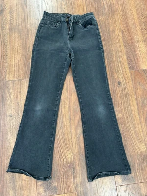 Svarta bootcut jeans  - Snygga svarta bootcut jeans och klassiska fickor. Jeansen har en lätt tvättad look och vida ben som ger en retrovibe. Perfekta för dig som vill ha en avslappnad men trendig stil. Materialet känns mjukt och följsamt.