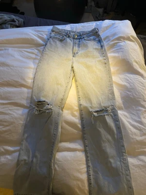 Ljusblå raka jeans med slitningar - Säljer ett par ljusblå jeans med raka ben och slitna detaljer på knäna. Perfekta för en avslappnad och trendig look. Jag som är 177cm lång, passar dom perfekt. Endast använd nån enstaka gång så i nyskick.