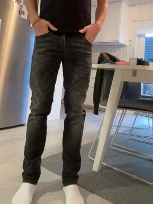 Svart/grå slim fit jeans Jack & Jones - Säljer ett par svarta slim fit jeans från Jack & Jones, modell Glenn. Jeansen har en smal passform och klassisk femficksdesign. Perfekta för dig som gillar en modern och stilren look. Materialet är mjukt och stretchigt för extra komfort. 