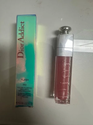 Dior Addict Lipgloss Flash 662 - Dior Addict Lipgloss i nyansen Flash 662 ger volym och glans till läpparna. Färgen är en skimrande rosa med plumping-effekt. Förpackningen är elegant med silverlock och genomskinlig plast som visar färgen. Innehåller 6,3 ml.