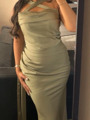Olivgrön långklänning med omlott - Snygg olivgrön långklänning med omlottdetaljer och unik axelbandsdesign. Klänningen har figurnära passform och drapering i midjan som ger en elegant siluett. Perfekt för dig som vill sticka ut med stil.