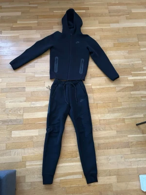 Svart Nike hoodie med dragkedja - Svart nike tech dress, ny pris 2500kr Aldrig använd. Storlek XS.