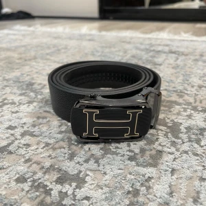 Läderbälte med automatiskt spänne – justerbar längd  - 📏 Storlekar: 130 cm & 135 cm Kan enkelt klippas i änden för perfekt passform.  🧵 Design: • Texturerat läder för en klassisk look • Slät läderfinish för en stilren, minimalistisk känsla (Bilder kan skickas vid intresse)  🔒 Automatiskt spänne: Smidigt klicksystem på insidan som sitter stadigt och enkelt justeras. Ger ett elegant och minimalistiskt uttryck.  🎨 Välj din logga: Flera loggor finns – välj din favorit. kolla min profil för alla alternativ 😊  📦 Snabb leverans 💬 Frågor? Hör av dig!