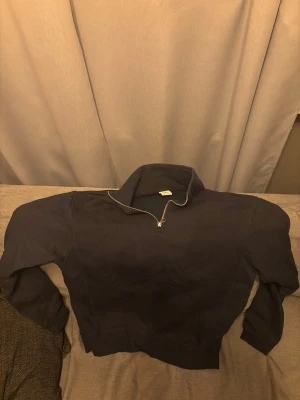 Mörkblå halvzip tröja - Mörkblå tröja med halv dragkedja och hög krage. Tröjan har långa ärmar och ribbade muddar vid ärmslut och nederkant. Perfekt för lager på lager och enkel att matcha med olika outfits.