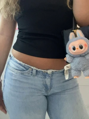 Ljusblå bootcut jeans - Säljer ett par ljusblå bootcut jeans med klassisk femficksdesign. Jeansen har en snygg, figurnära passform upptill och utsvängda ben nertill. Perfekta till sneakers eller boots och lätta att matcha med olika toppar.