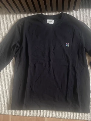 Svart långärmad t-shirt Tonisure - Svart långärmad t-shirt från Tonisure med färgglatt Copenhagen Teddy-logo broderat på bröstet. Klassisk rund hals och clean look som funkar till allt. Tillverkad i mjuk bomull för skön känsla hela dagen.finns i olika storlek 1st S 1st M 2st L och 1st XL