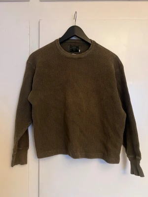 Olivgrön stickad tröja Diesel - Olivgrön stickad tröja från Diesel med grov, rutmönstrad struktur. Tröjan har rund halsringning, långa ärmar och ribbade muddar. Perfekt för lager på lager och enkel att matcha med jeans eller byxor.