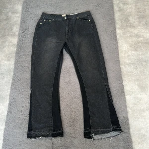 Svarta jeans med råa kanter - Svarta jeans från Gallery Dept. med klassisk femficksdesign, raka ben och råa, fransiga benslut för en edgy look. Jeansen har guldfärgade nitar och en något tvättad finish som ger en cool vintagekänsla. Perfekta för dig som gillar streetstyle.