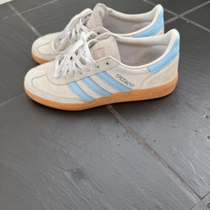 Adidas Spezial sneakers ljusblå/beige - Adidas Spezial sneakers i mocka med ljusbeige ovandel, ljusblå detaljer. Jag säljer då de inte kommer till användning mer. De är använda men fortfarande i bra skick🤍Nypris ca 1300 säljer för 750. Storlek 37 1/3 men passar mig som brukar ha 38