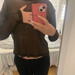 Glittrig meshtröja från Weekday - Säljer en svart/brun meshtröja från Weekday i storlek S. Tröjan är tunn och transparent med glittriga guldiga detaljer i tyget. Långärmad och perfekt att styla lager på lager eller till ett par snygga byxor.