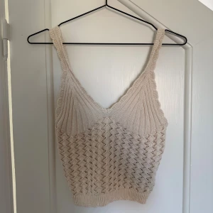 Beige virkad linnetopp från H&M - Supersöt beige virkad linnetopp från H&M i storlek  S. Toppen har ett snyggt hålmönster och ribbade detaljer vid bysten och nederkanten samt en v-ringning. Perfekt till jeans eller kjol för en chill sommarlook!🥰