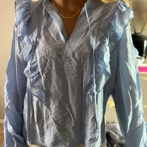 Blå blus - Blå blus med detaljer i ett tunt material med snören som man kan knyte eller ha hängande🥰