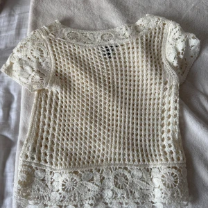 Vit spetsblus från H&M XS - Superfin vit blus från H&M i storlek XS. Blusen är virkad med blommiga spetsdetaljer och har korta ärmar. Den är genombruten med ett unikt mönster och har en rund halsringning. Perfekt för en somrig och bohemisk look.