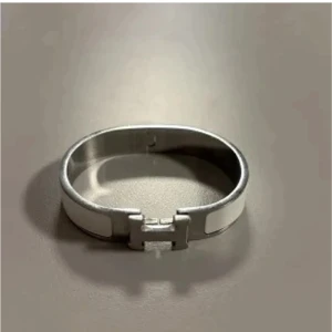 Silverfärgat armband med H-detalj - Stilrent armband i silverfärg med en tydlig H-detalj framtill. Armbandet har en enkel och modern design som passar perfekt till dig som gillar minimalistiska accessoarer.