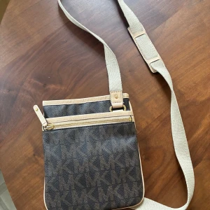 Michael Kors crossbody bag  - Brun Michael Kors axelremsväska med axelrem och dragkedja upptill. Väskan har ett fack med magnetknäppning inuti. Använd, men överlag bra skick. 19x22 cm stor.