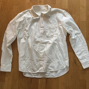 Vit klassisk skjorta från East West - Snygg vit skjorta från East West med klassisk krage och bröstficka. Skjortan har lång ärm och knappar hela vägen framtill. Perfekt för dig som gillar enkel och stilren design. Materialet är mjuk bomull som känns skönt mot huden. Helt ny!