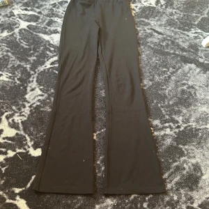 Svarta bootcut byxor i bomull - Svarta bootcut byxor med hög midja och stretchig känsla. Tillverkade i mjukt bomullsmaterial som sitter skönt och följer kroppen. Perfekta för dig som gillar en klassisk look med lite utsvängda ben.