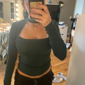 Mörkgrön ribbad polotopp från Zara - Säljer en mörkgrön ribbad polotopp från Zara i storlek S. Toppen har lång ärm, croppad passform och en cool öppen rygg med choker-detalj vid halsen. Perfekt för dig som gillar trendiga och unika plagg med snygg siluett. Köpte från sellpy men har aldrig använt så prislapp kvar!