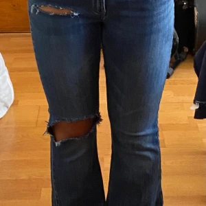 Blå bootcut jeans från Lindex - Ge förslag❗️Snygga blå jeans från Lindex med bootcut-ben och slitna detaljer på låret och vid fickan. Storlek 38 men sitter som 34. Klassisk femficksmodell med bälteshällor och dragkedjegylf. Jeansen har en cool tvätt och är perfekta för en avslappnad stil.