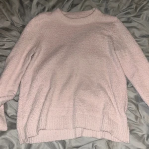 Ljusrosa stickad tröja - Supermjuk och fluffig ljusrosa stickad tröja med rund hals och långa ärmar. Perfekt för kyliga dagar och enkel att matcha med jeans eller kjol. Tröjan har en avslappnad passform och ribbade muddar vid ärmslut och nederkant.