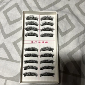 Svarta lösögonfransar i 10-pack - Säljer ett set med 10 par svarta lösögonfransar i klassisk bågform. Fransarna är täta och ger en dramatisk look med markerad volym och längd. Perfekta för att lyfta din sminkning och skapa en intensiv blick. Kommer i en vit ask.