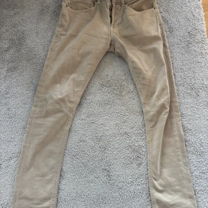 Beige skinny byxor från Dondup - Snygga beige byxor från Dondup i modellen George Skinny Fit. Byxorna har klassisk femficksdesign, smal passform och är tillverkade i bomull med en liten mängd elastan för extra stretch. Perfekta för dig som gillar en stilren och modern look.
