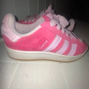 Adidas Campus rosa sneakers - Säljer ett par Adidas Campus sneakers i rosa mocka med ljusrosa detaljer och klassiska tre ränder på sidan. Skorna har platt sula, rund tå och snörning. Perfekta för dig som vill sticka ut med färg på fötterna.