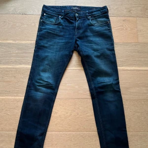 Mörkblå skinny jeans Scotch & Soda - Mörkblå jeans från Scotch & Soda, modell Tye. Snygg fit med klassiska fem fickor och gul detaljsöm på bakfickan. Jeansen har en stilren look med lätt tvättade partier och är tillverkade i stretchig denim för extra komfort.