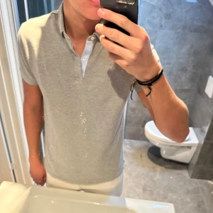 Grå/beige pikétröja från Massimo Dutti - Riktigt snygg piké från Massimo dutti. Pikén är i riktigt bra skick och har inga skador. Jag är 188cm o bär storleken M vilket jag anser är optimalt. Hör av er vid frågor;)