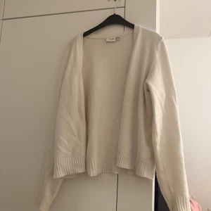 Vit kofta från SALT  - Enkel/ stilig  kofta från SALT storlek L (vit/creme färg).  Koftan är öppen framtill, har långa ärmar och ribbade muddar vid ärmslut och nederkant. Perfekt för alla looks. Materialet är mjukt och skönt samt stretchigt. Som ni ser på sista bilden så börjar det noppa vid ärmarna/ släpper fibrer  lite här o där, inget som påverkar användningen. Koftan är köpt ganska nyligen,  inte så många gånger använd. Koftan passar egentligen alla oavsett storlek.