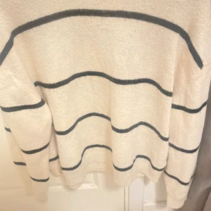 Randig vit stickad tröja från H&M - Säljer en vit stickad tröja från H&M i storlek M med svarta horisontella ränder. Tröjan har en klassisk rund halsringning och långa ärmar. Perfekt för dig som gillar en enkel men stilren look.😍🙏🏽