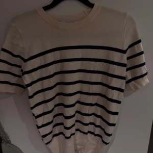 Randig vit kortärmad tröja - Vit randig t-shirt från Zara. Den är creme vit med mörkblåa ränder💗 en liten fläck längst ned på tröjan som jag ej fått bort. 