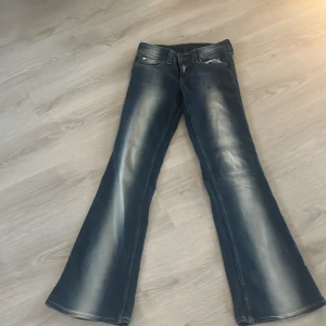 Blå bootcut jeans med slitningar - Snygga blå jeans med bootcut-modell och markerade slitningar längs benen. Klassisk femficksdesign och låg midja. Jeansen har en cool tvättad look och är tillverkade i stretchigt denim för skön passform.