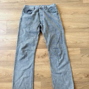 Grå jeans från HOPE, rak modell - Grå jeans från HOPE i klassisk rak modell. Jeansen har fem fickor, bälteshällor och stängs med och knapp. Tillverkade i bomull med en snygg tvättad finish som ger en cool vibe. Perfekta för dig som gillar stilrena och tidlösa jeans. 