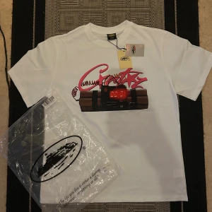 Vit cortiez t shirt med notime4luv där bak - Säljer en vit t-shirt från Notime4luv med tryck framtill av graffiti-texten 'Crtz” och en digital bombillustration. Baksidan har ett stort svart tryck med texten 'NOTIME4LUV'. Klassisk passform och rund hals. Materialet är mjuk bomull.