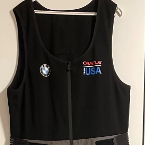 Sail Racing GORE-TEX täckbyxor Team USA - Säljer ett par grå täckbyxor från Sail Racing Team USA med GORE-TEX-material. Byxorna har hög midja, svart överdel med dragkedja framtill och coola loggor från BMW, Oracle och USA. Fickor med röd dragkedja och justerbara kardborreband i midjan. Pris kan diskuteras vid snabb affär.
