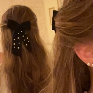 Svart hårklämma rosett med pärlor - Gullig svart rosett till håret med pärldetaljer, fäst med metallspänne. Rosetten är gjord i ett tunt, tyg och dekorerad med vita pärlor i olika storlekar. Jätte söt o gullig men kommer inte till användning. Har mycket tjockt hår o så som jag har på bilden håller den hela dagen.✨väldigt tunt tyg så de är dubbel tyg på den (de är därför de ser ut som lite vit fläckar på bilden såg jag men de är de inte i verkligheten 
