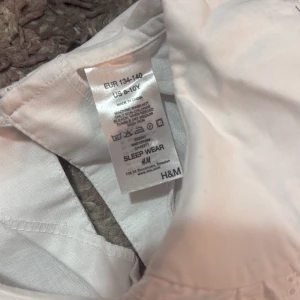 Lucia klänning  H&M - Säljer en vit lucia klänning från H&M i storlek 134-140. Klänningen har lång ärm med resår vid ärmslut och en söt spetsdetalj på den rundade kragen. 