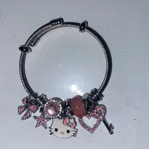 Hello Kitty armband med rosa berlocker - Snyggt silverfärgat armband med flera berlocker, bland annat Hello Kitty, stjärna, rosett, hjärta och nyckel. Berlockerna är dekorerade med rosa stenar och detaljer.💕🥰