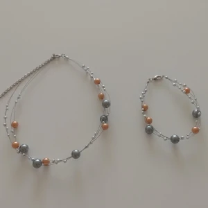 Set med halsband och armband med pärlor - Snyggt set med halsband och armband i silverfärgad metalltråd med pärlor i silver, guld och vitt. Flera tunna trådar med pärlor i olika storlekar ger ett coolt och luftigt uttryck. Perfekt för dig som gillar att mixa färger och detaljer.