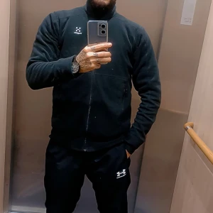 Svart fleechoodie från Haglöfs mycket bra skick  - Svart fleece hoodie  från Haglöfs med hög krage och hel dragkedja framtill. Jackan har långärmade ärmar och en stilren design med diskret logga på bröstet. Perfekt för kyliga dagar och enkel att matcha med andra plagg. Använd ett fåtal ggr all plagg förvaras fint och har hand om dom med kärlek :)st smal finns fler bilder vid intresse 