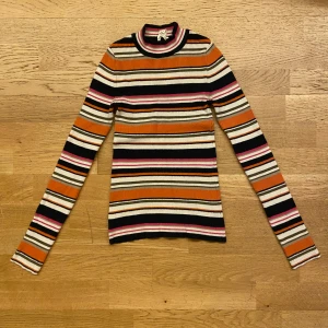 Randigt ribbad tröja Holly & White XS - Superfin ribbad tröja från Holly & White i storlek XS. Den är långärmad, har en högre hals och sitter tight. Perfekt för dig som gillar retrovibbar och vill sticka ut lite extra.