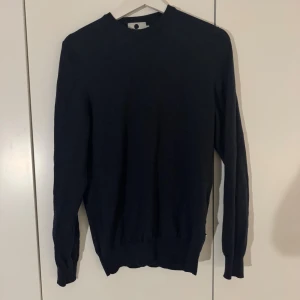 Nn07 stickad tröja - En stilren mörkblå stickad tröja med rund halsringning och långa ärmar. Perfekt för lager-på-lager och enkel att matcha med både jeans och chinos. Tröjan har en klassisk passform och ribbade muddar vid ärmslut och nederkant.