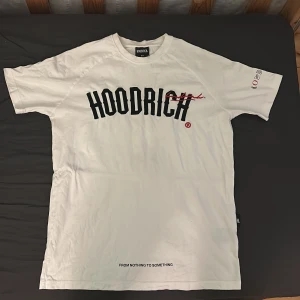 Vit HOODRICH t-shirt med tryck XS passar som S - Vit t-shirt från HOODRICH i bomull med svart och rött tryck framtill och textdetaljer på ryggen. Klassisk passform med korta ärmar och rund hals. Snygga grafiska detaljer och statement-prints gör den här t-shirten till ett riktigt streetwear-plagg.