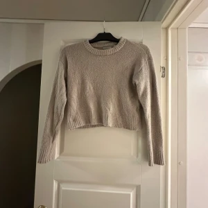 Beige croppad stickad tröja 157 - Mysig croppad stickad tröja i beige från laget 157. Tröjan har rund halsringning, ribbade muddar och är långärmad. Är inte stickig, är väldigt mjuk!