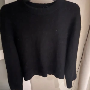 Svart stickad tröja med rund hals - En enkel och stilren svart stickad tröja med rund hals och långa ärmar. Perfekt att matcha med jeans eller kjol för en chill look. Mjuk och skön känsla, passar dig som gillar klassiska basplagg.