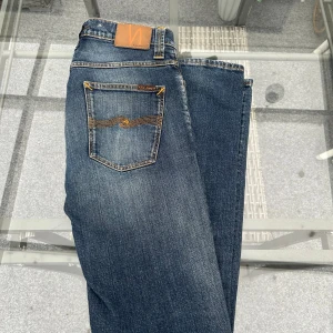 Nudie Jeans W32 L34 – Snygg tvätt - Nudie Jeans, storlek W32 L34. Snygg tvätt med naturligt slitage på rätt ställen, ger den där perfekta använda looken. Bra passform – slim/regular. Sköna att ha på och håller formen fint. I bra skick. Säljs bara pga för stora för mig.  💙 Äkta Nudie 🧵 Klassisk bakficka-brodyr 🔹Passar både casual och street 